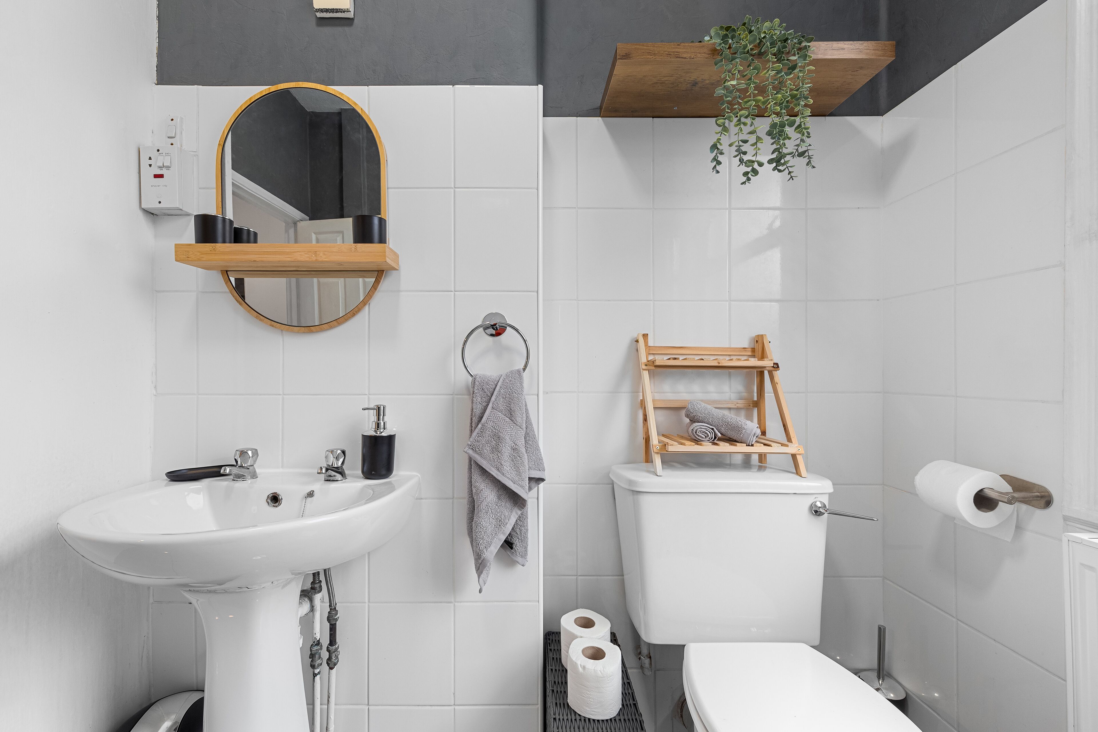 Moderni kylpyhuone, jossa on valkoinen pesuallas, peili, wc-istuin ja pyyheteline.
