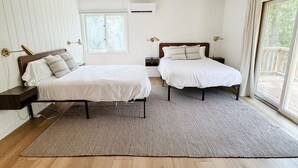 A bedroom with two beds, a ceiling fan, a window, and a view of the outdoors. - Downtown Sister Bay | Arcade, Deck, Fire Pit (Sister Bay)