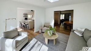 A modern living room with a skylight, a kitchen in the background, and a dining area. - Downtown Sister Bay | Arcade, Deck, Fire Pit (Sister Bay)