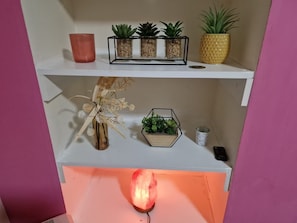 Decorative items and plants adorn the shelf and cabinet.