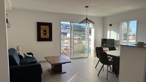 Ein modernes Wohnzimmer mit Sofa, Esstisch und Küchenbereich.