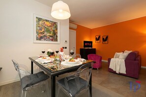 A dining area with a table set for two, a sofa, and a Netflix sign on the wall.