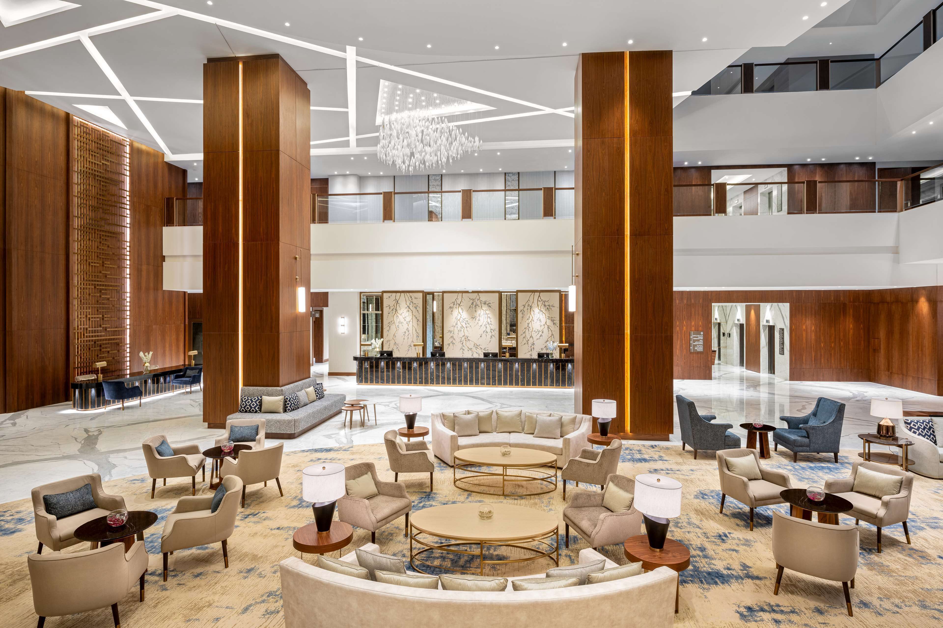 A spacious lobby with a central seating area, a reception desk, and a chandelier.