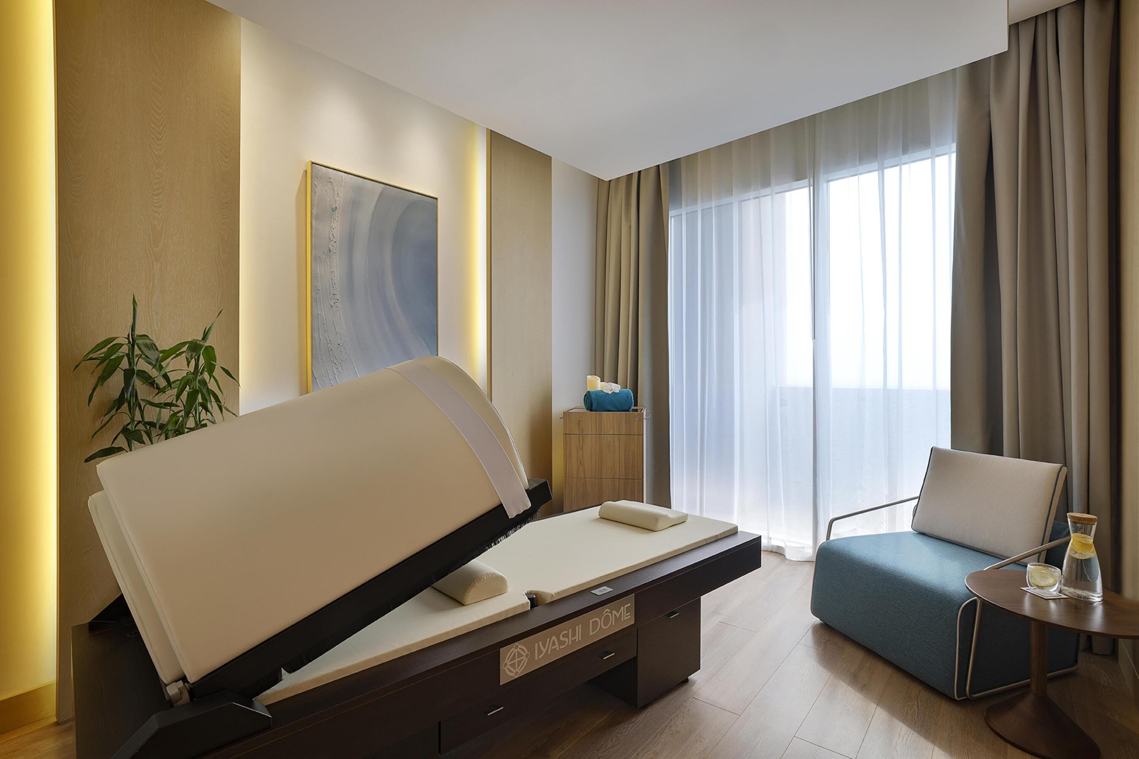 Habitació d'hotel moderna amb un llit, un sofà, una taula petita amb un got i una planta.