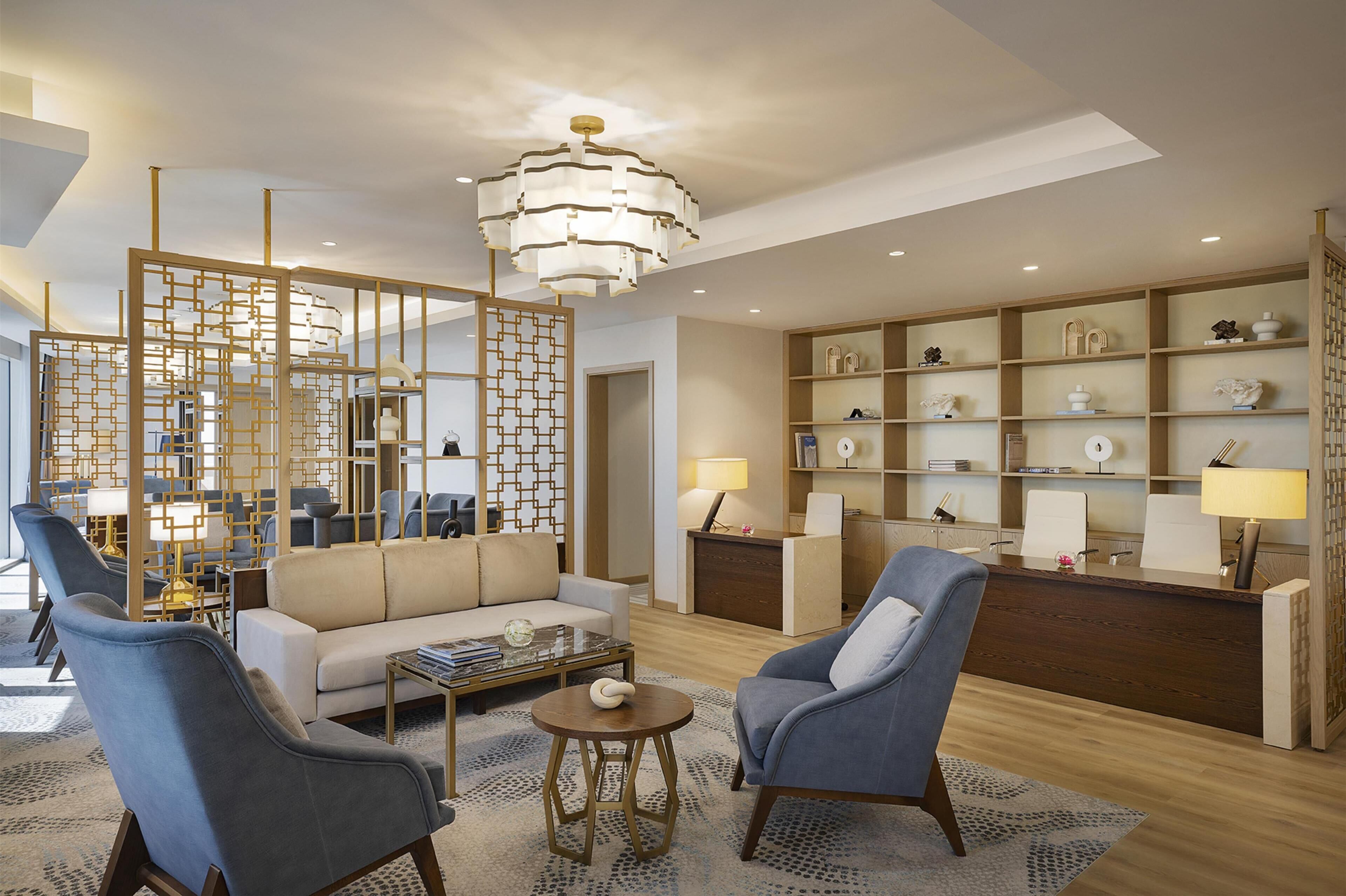 A modern hotel lobby with a reception desk, seating area, and decorative elements.
