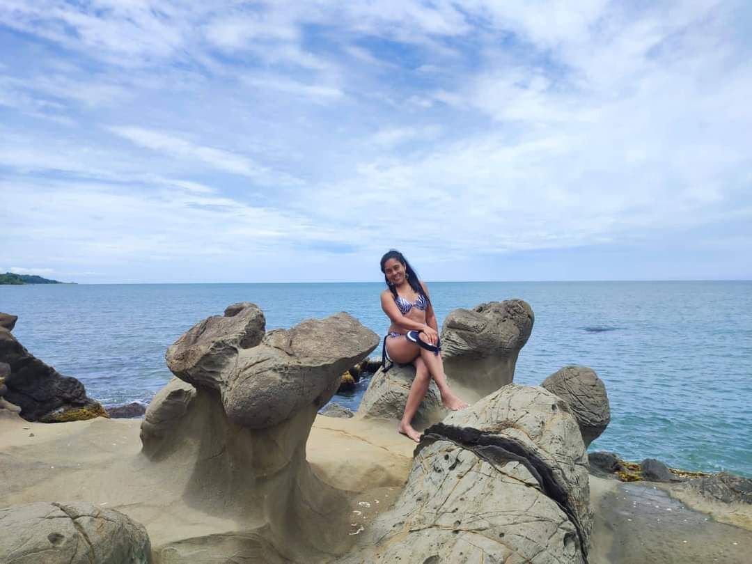 A person sitting on a rocky outcrop by the sea.