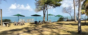 A beach with a sign reading "ENLANTI" and several green umbrellas providing shade. - Encanto de la Vega Hotel (Moñitos)