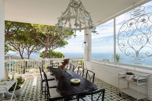 A dining area with a table and chairs, a decorative metal tree, and a view of the sea.