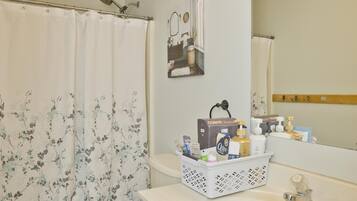 Une salle de bain avec un rideau de douche, des toilettes, un lavabo et un meuble-lavabo.