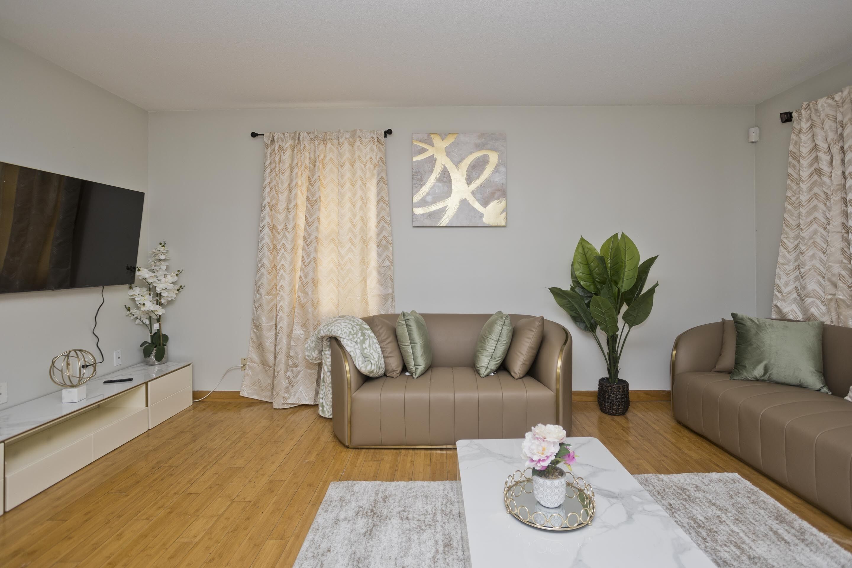 Un salon moderne avec un canapé marron, une table basse blanche et une grande plante en pot.