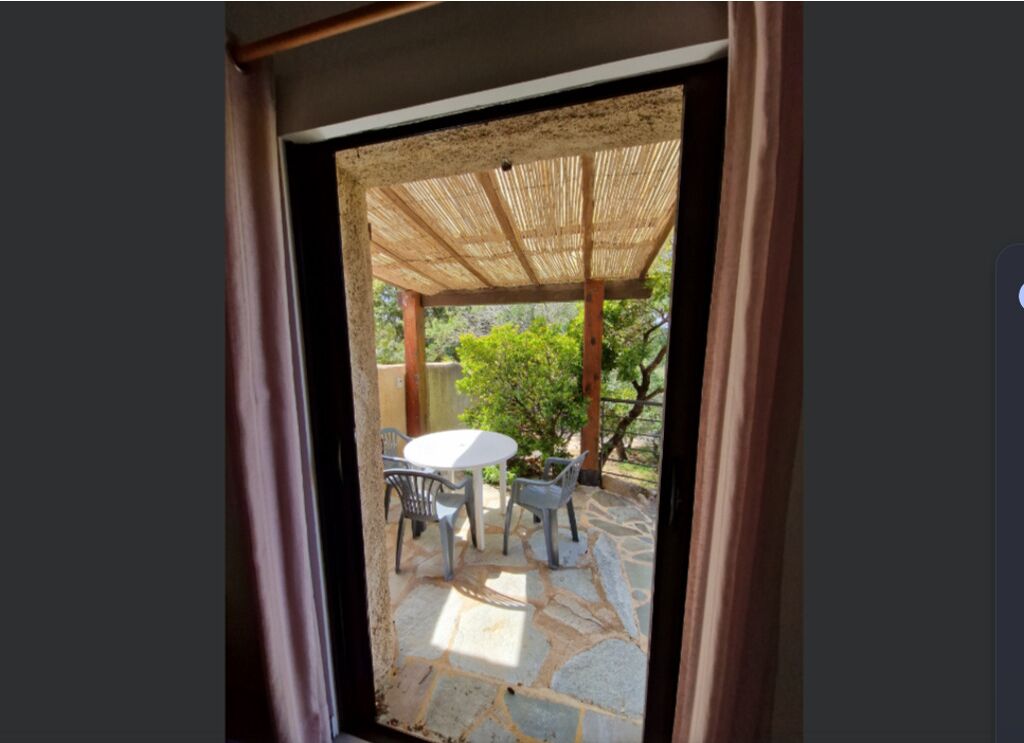 An outdoor patio area with a stone floor, a round table, and two chairs.