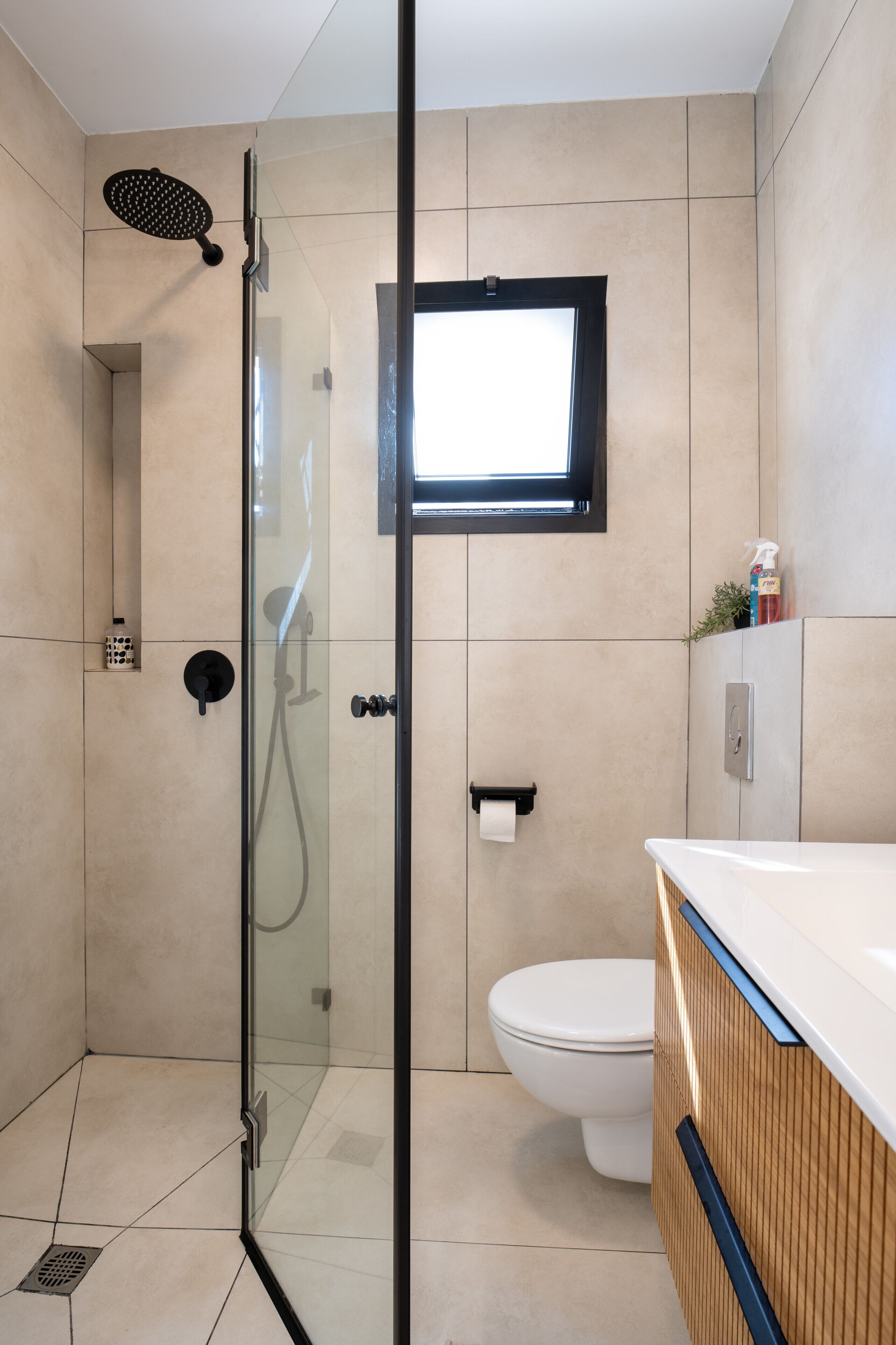 Ein modernes Badezimmer mit einer Duschkabine, einer Toilette und einem Waschbecken mit Holzschrank.