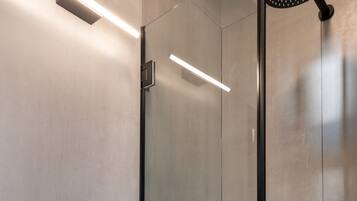 A modern bathroom with a white vessel sink, a handheld showerhead, and a glass-enclosed shower stall.