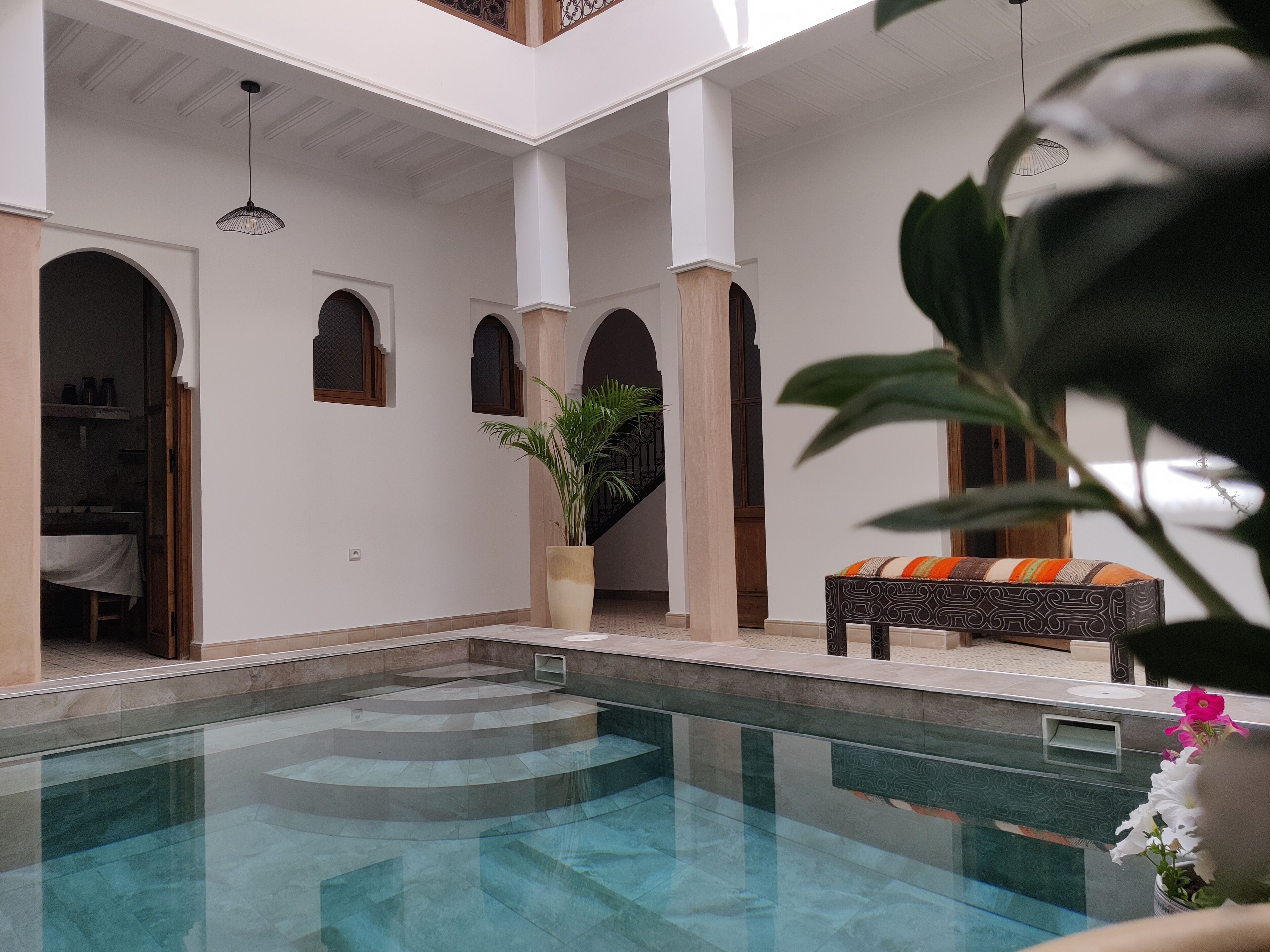 A pool area with a seating area, a staircase, and a potted plant.