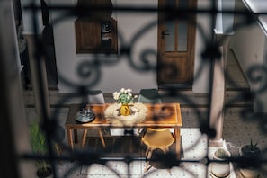 A dining area with a wooden table, chairs, and a vase of flowers. - Riad Bab Aljana (Marrakech)