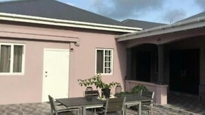 A house with a covered patio area, a dining table with chairs, and potted plants. - Modern spacious accommodation 1 (Cedar Grove)