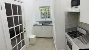 A compact kitchen with a gas stove, a microwave, a sink, and a window above it. - Modern spacious accommodation 1 (Cedar Grove)