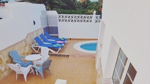 Terraza en la azotea con piscina, sillas de descanso azules y baranda blanca.