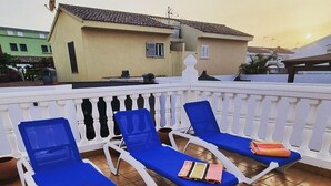 Una terraza con sillones azules y barandilla blanca.