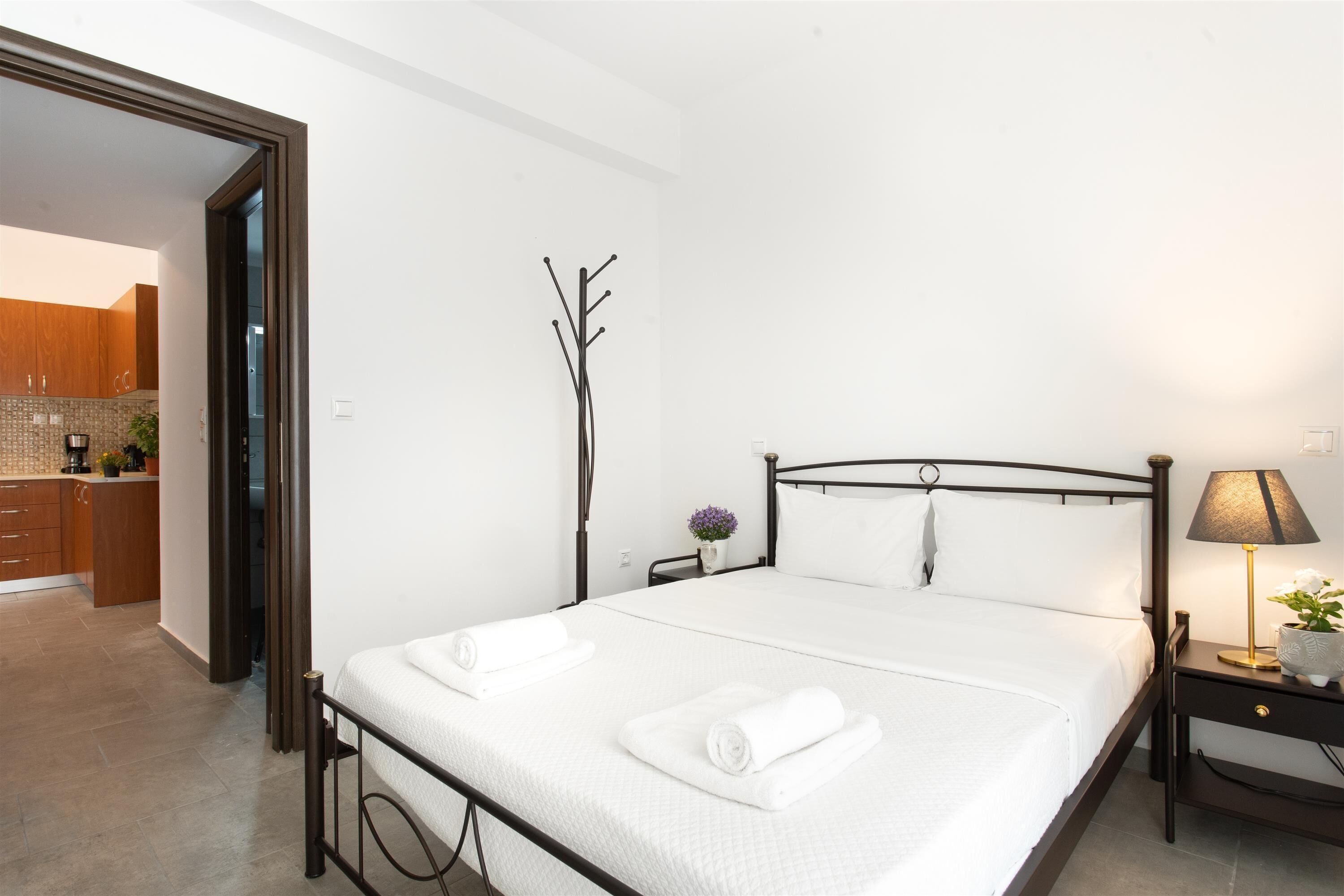 Un dormitorio moderno con cama, mesita de noche, lámpara y vistas a la cocina.