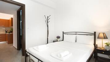 Un dormitorio moderno con cama, mesita de noche, lámpara y vistas a la cocina.