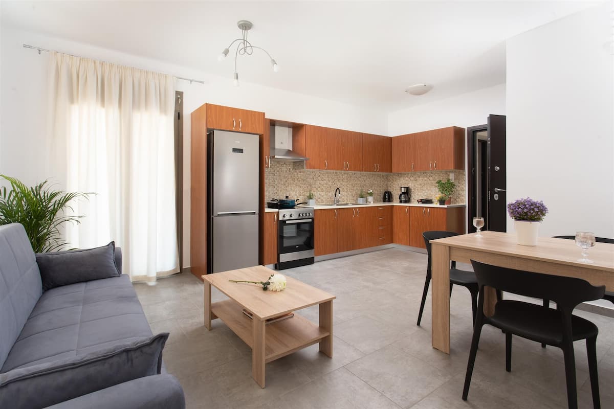 A modern kitchen with wooden cabinets, a stainless steel refrigerator, and a dining area with a table and chairs.