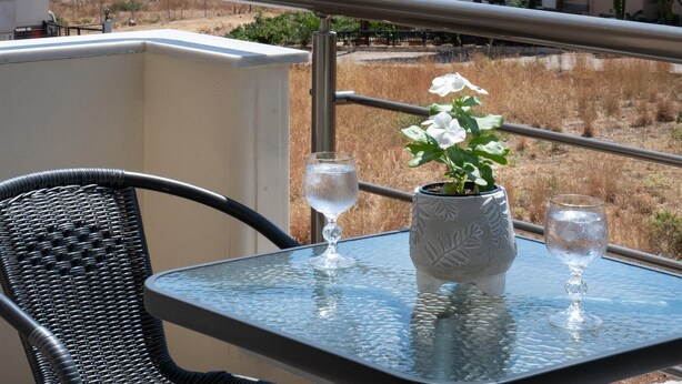 A balcony with a table, a chair, and a potted plant. - Tulipa Suites (Monemvasia)