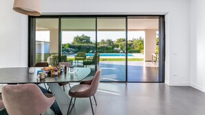 A modern dining area with a glass door leading to a poolside.