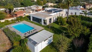 A modern house with a swimming pool, solar panels, and a well-maintained garden.
