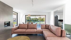 A modern living room with a large L-shaped sofa, a round coffee table, and a minimalist design.