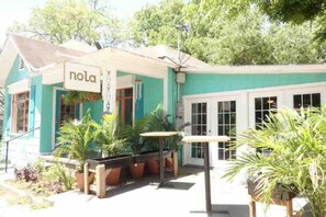 A building with a sign reading "nola" and a covered outdoor seating area with tables and chairs.