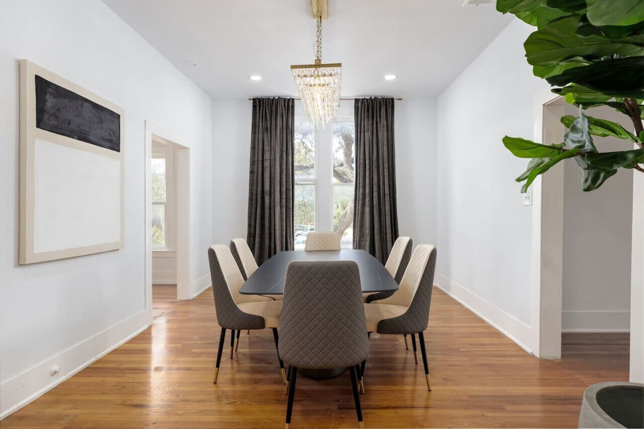 A dining area with a rectangular table, six chairs, and a chandelier.