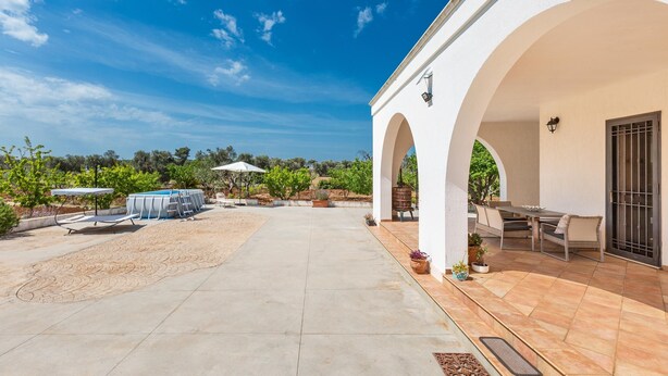 A covered patio with a pool, outdoor seating, and a view of the surrounding landscape. - 2942 Villa Cucunci by Barbarhouse (Ostuni)