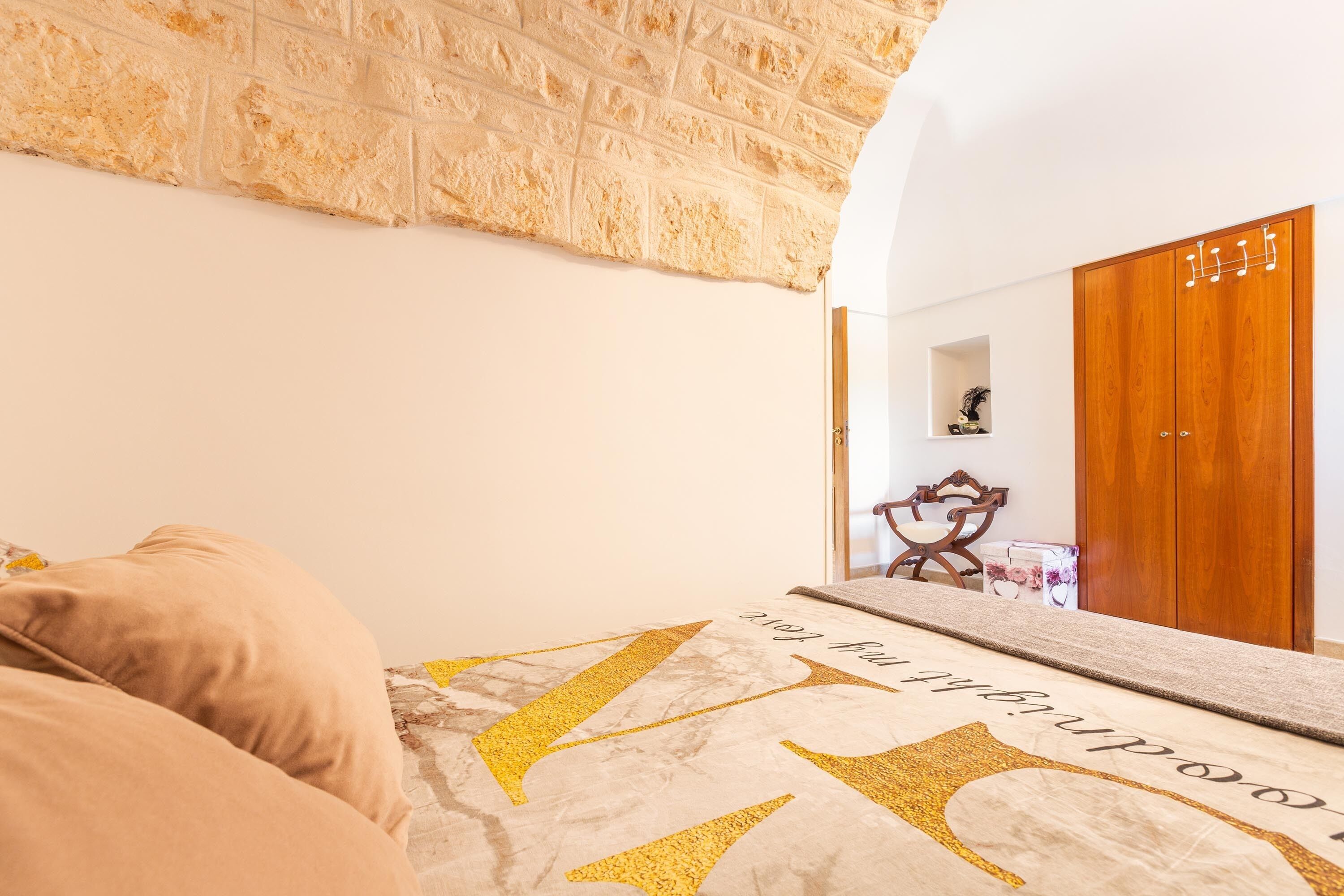 Une chambre à coucher avec un lit, une armoire en bois et un mur en pierre.