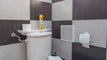 Een badkamer met een toilet, een handdoek, een toiletrolhouder en een raam.