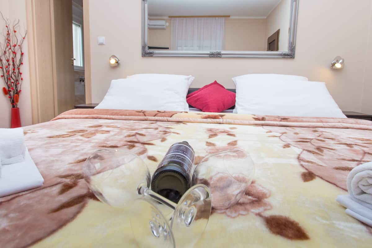 Ein Hotelzimmer mit einem Bett, einem Spiegel und einer Weinflasche auf dem Bett.