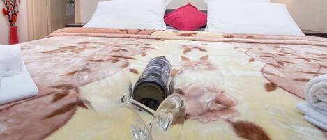 A hotel room with a bed, a mirror, and a bottle of wine on the bed.