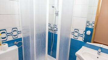 Ein Badezimmer mit Duschkabine, Toilette, Waschbecken und blauen Fliesen.