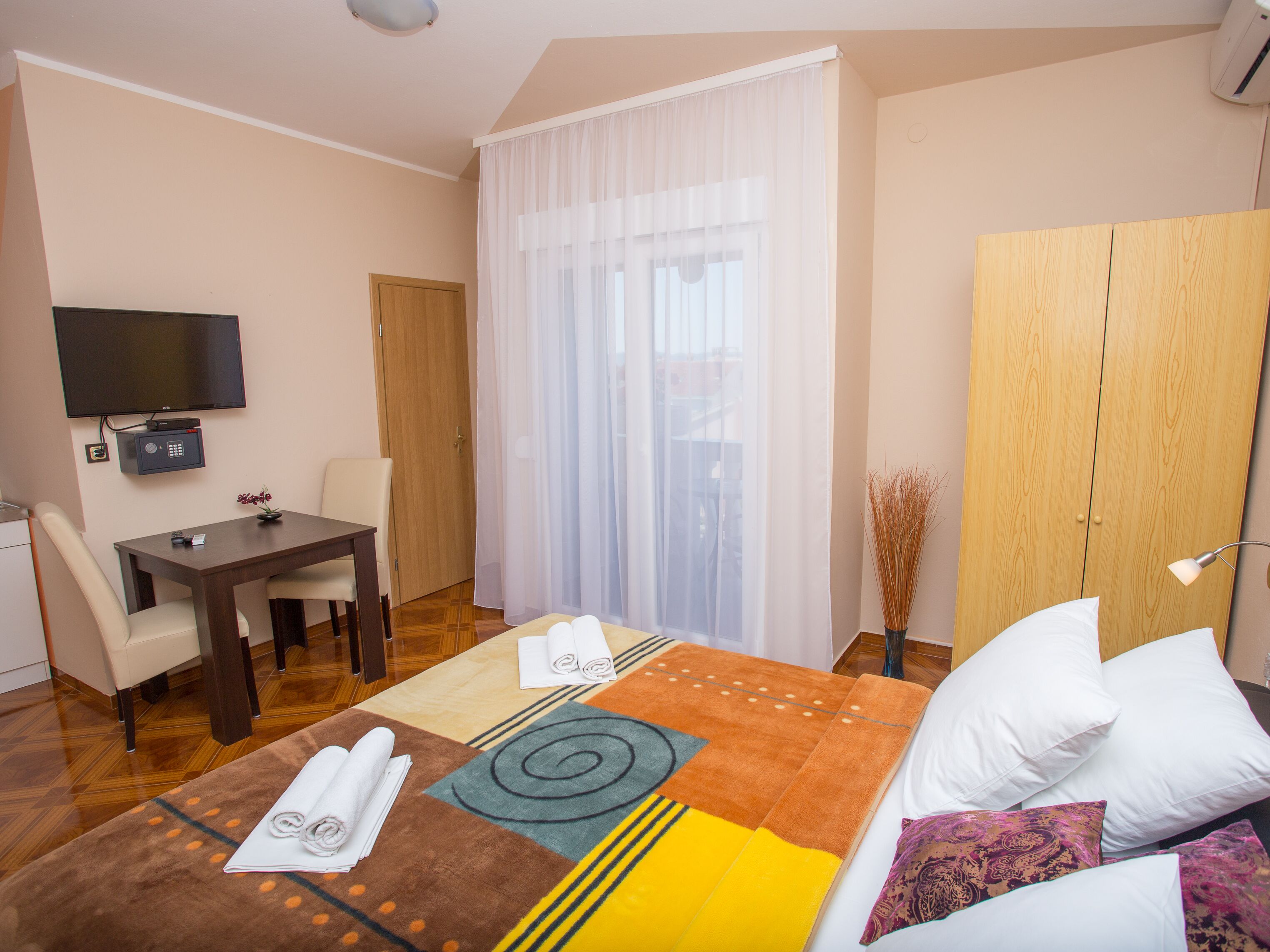 Une chambre d’hôtel comprenant un lit, un bureau, une chaise, une télévision et une armoire.