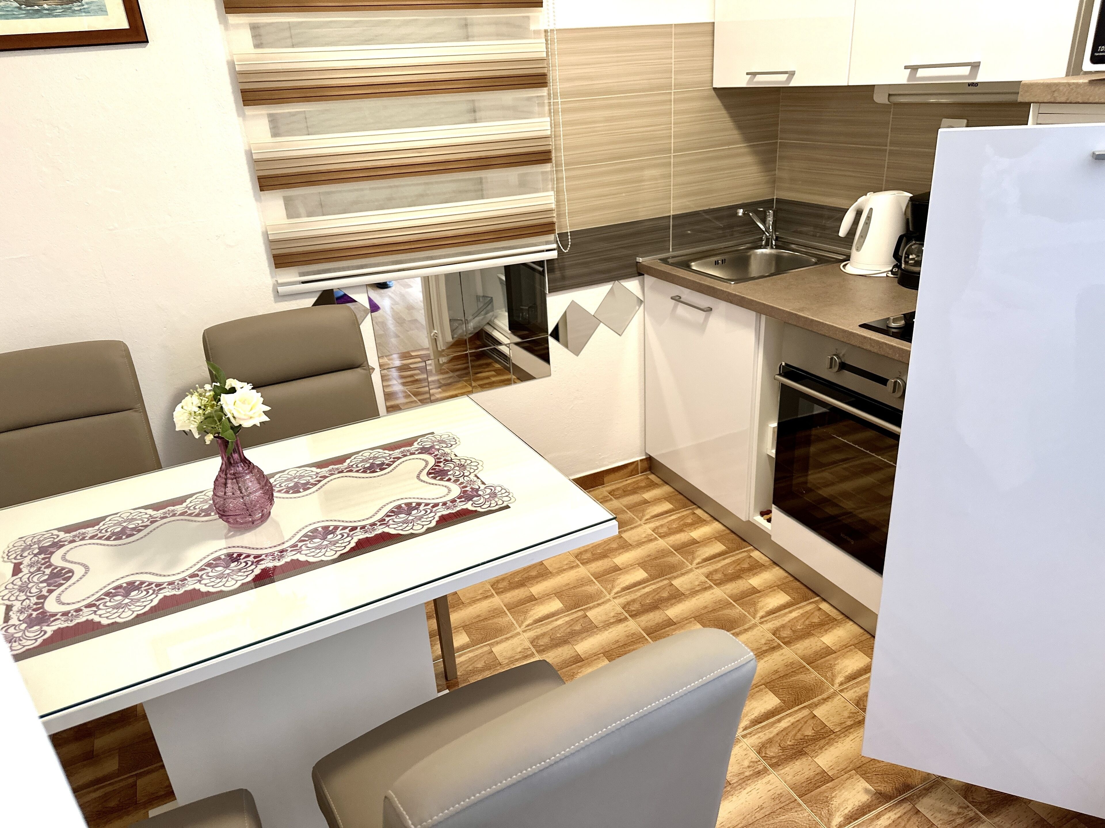 A compact kitchen with a dining area, featuring a sink, stove, and a refrigerator.