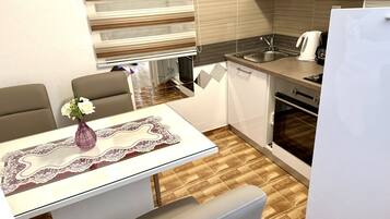 A compact kitchen with a dining area, featuring a sink, stove, and a refrigerator.