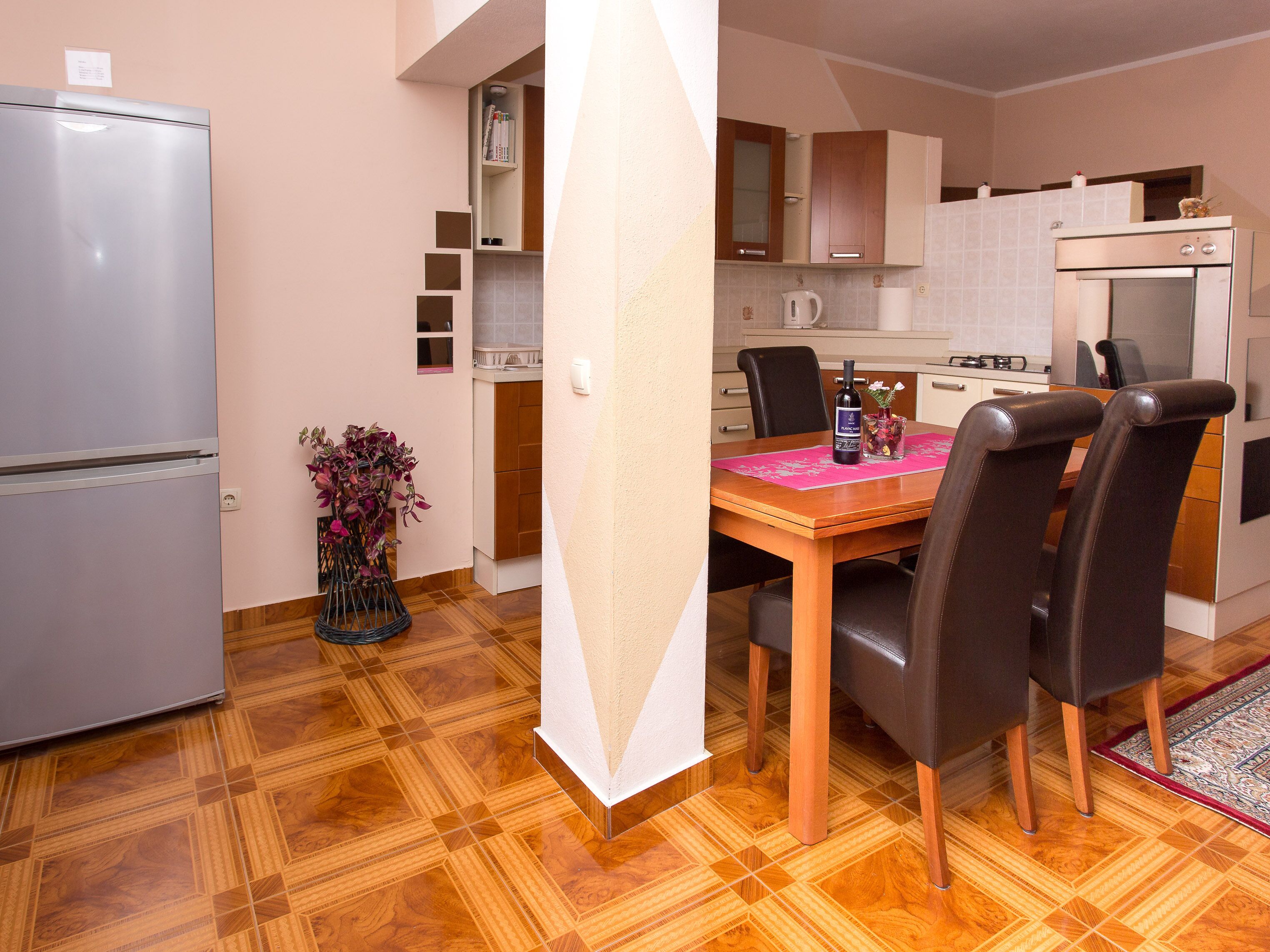 A compact kitchen with a dining table, chairs, a refrigerator, and a coffee machine.