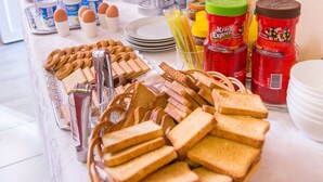 Buffetpöydässä on tarjolla monenlaista ruokaa, kuten leipää, kananmunia ja erilaisia lisukkeita.