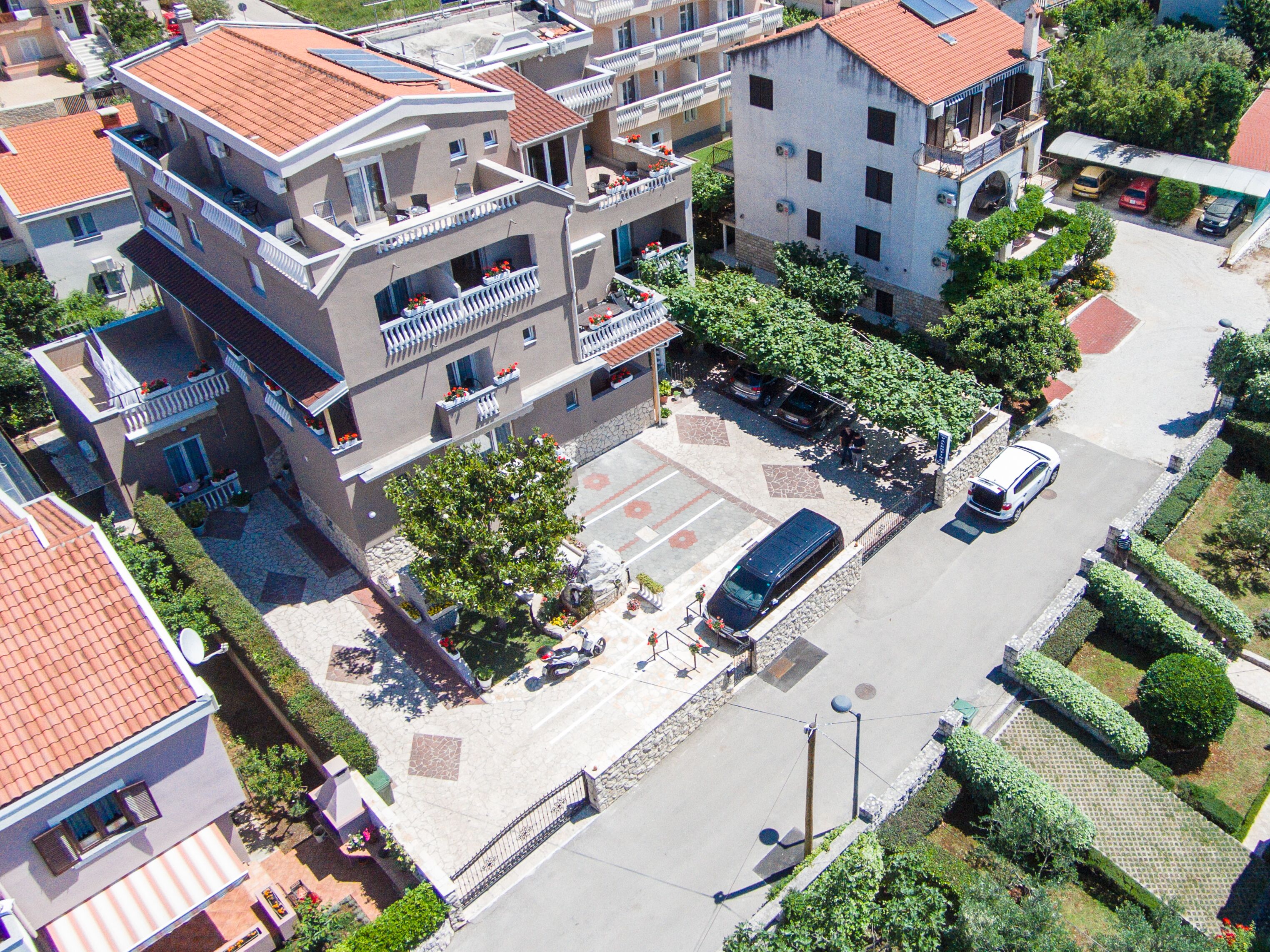 An aerial view of a residential area with multi-story buildings, a parking lot, and a street.