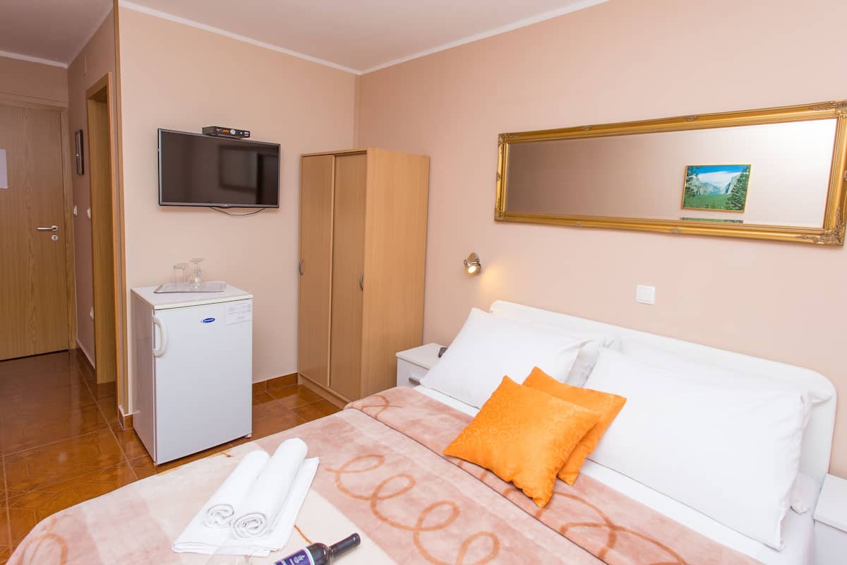 Ein Hotelzimmer mit Bett, Fernseher, Kleiderschrank, Schreibtisch und einer Waschmaschine.