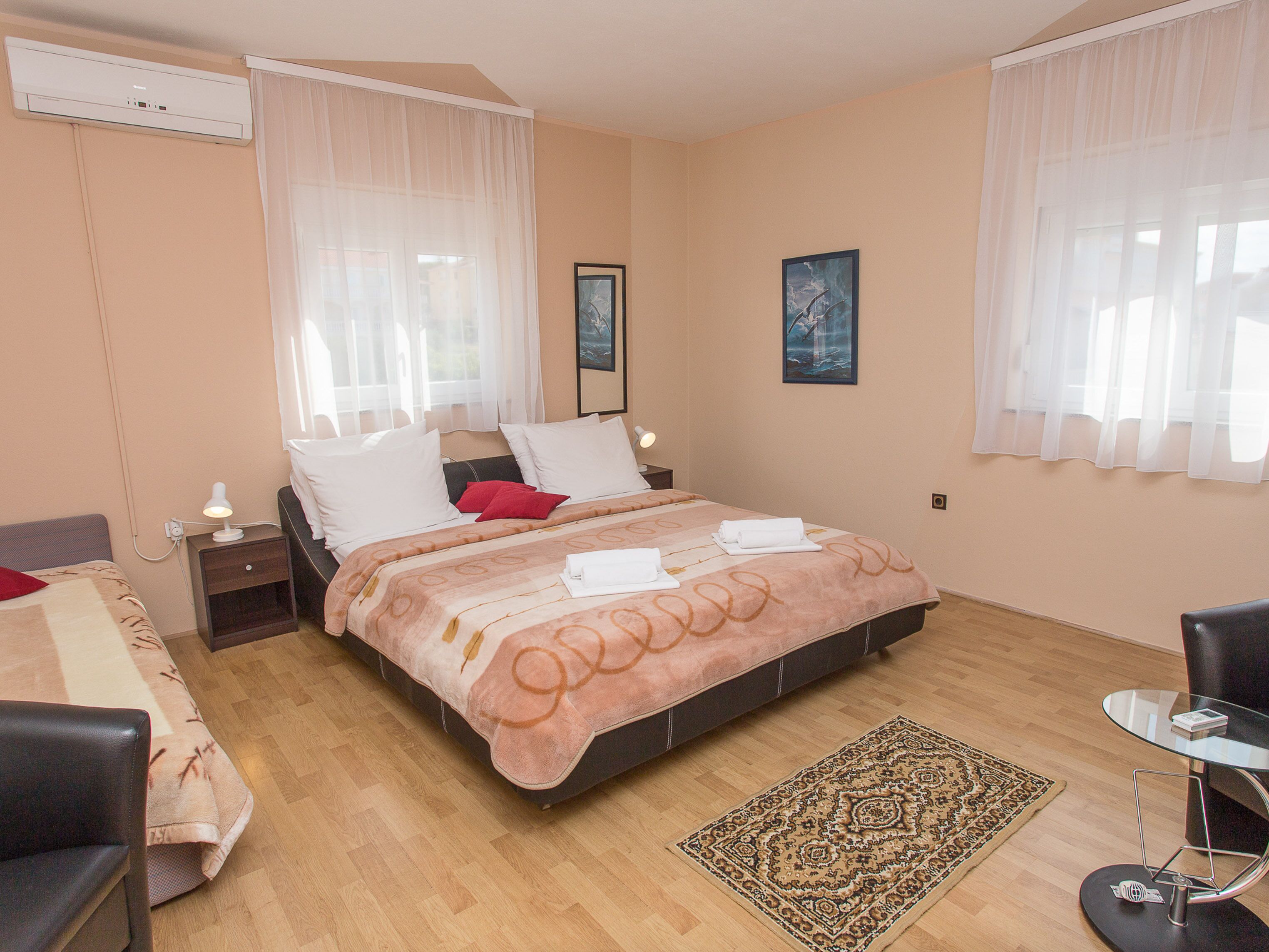 Une chambre à coucher bien rangée, avec un lit, des tables de chevet, une chaise, une table en verre et un tapis.