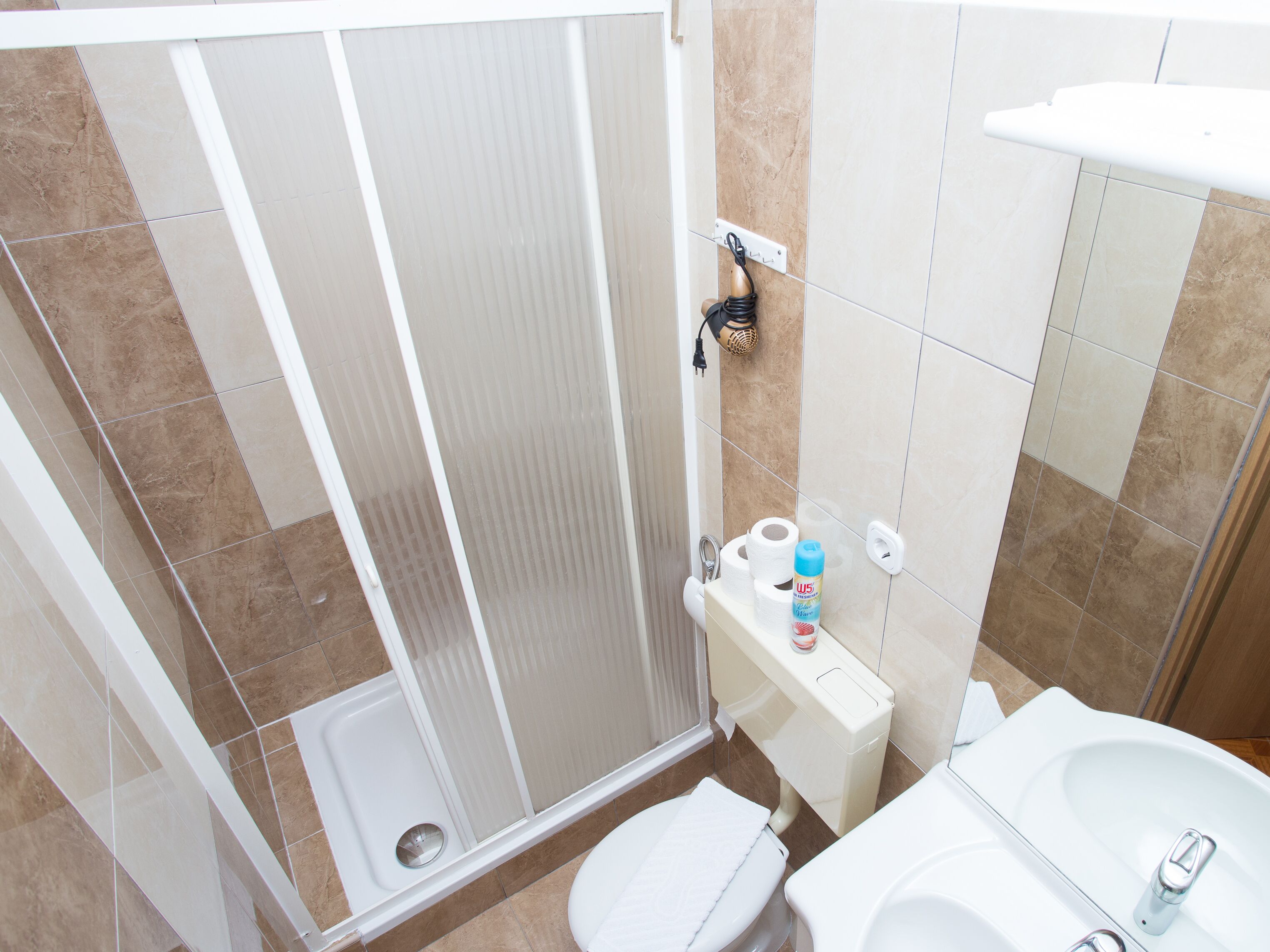 Ein Badezimmer mit Dusche, Toilette, Waschbecken und einem Handtuchhalter.
