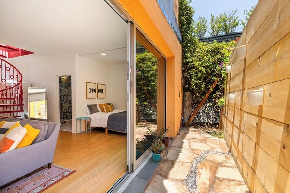 A modern interior with a bed, a sofa, and a red spiral staircase. - Artistic Venice Beach Canals Studio w/Rooftop & Sauna! (Marina del Rey)