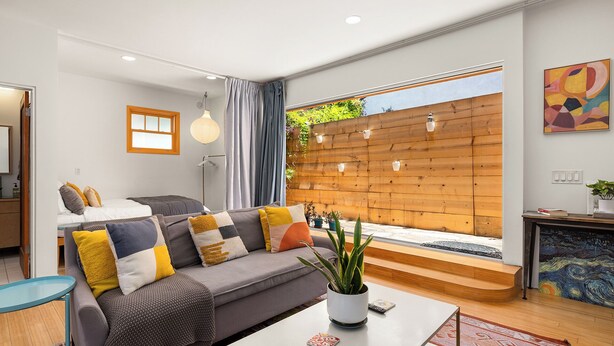 Una sala de estar moderna con un sofá gris, una mesa de centro y una pared de madera con luces colgantes.