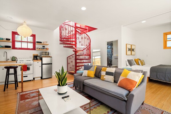 A modern apartment with a spiral staircase, a kitchen, a living area with a sofa, and a dining area.